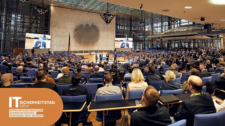 Plenarsaal voller Menschen bei Vortrag vor dem Bundesadler