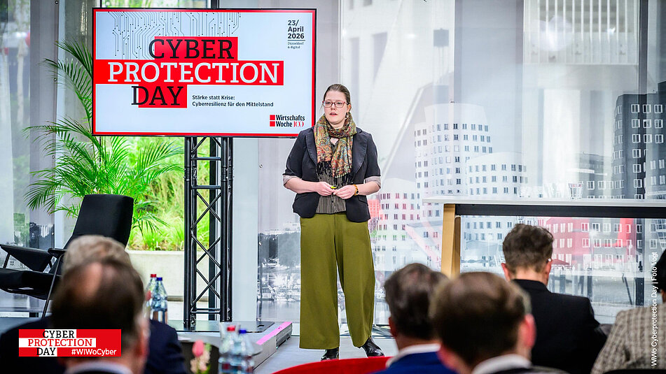 Referentin auf der Bühne neben einem Tisch vom Wiwo Cyberprotection Day 2026