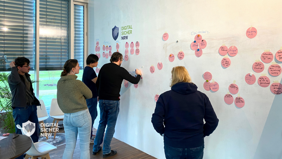 DIGITAL.SICHER.NRW Workshop – Personen stehen vor einer Whiteboard-Wand