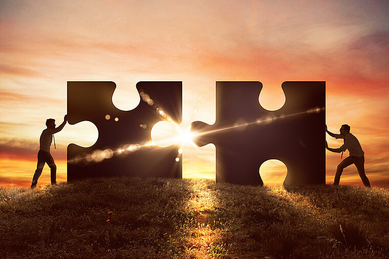 Zwei Personen schieben je ein Puzzleteil zusammen