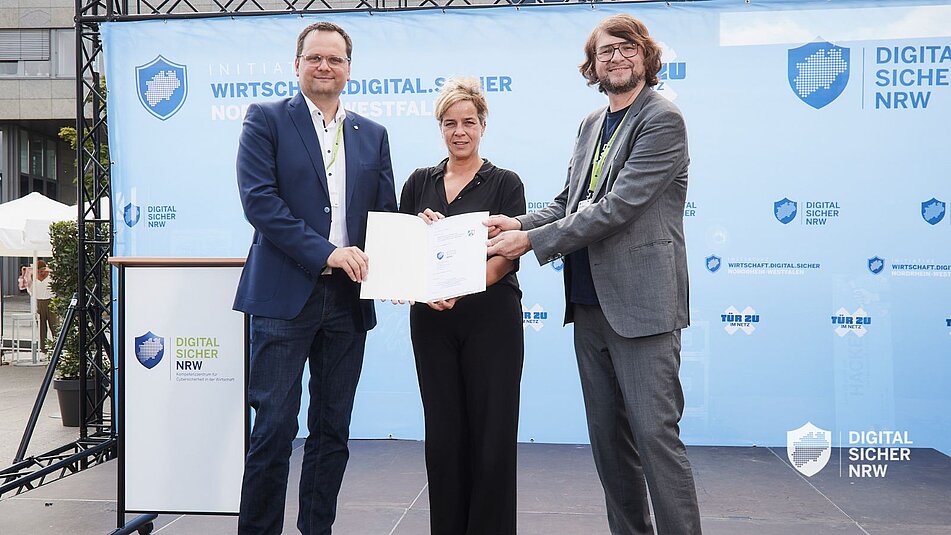 Sebastian Barchnicki, Mona Neubaur und Peter Meyer halten den Vertrag in den Händen